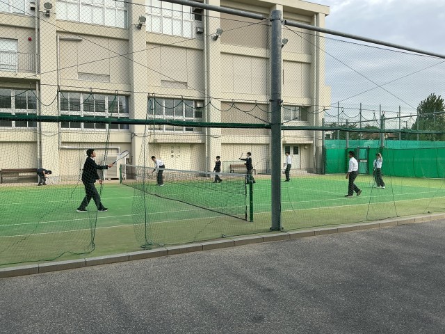 テニスコートでテニスをしている生徒たち