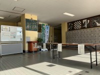 昇降口に置かれた受付台とホワイトボードの案内表示