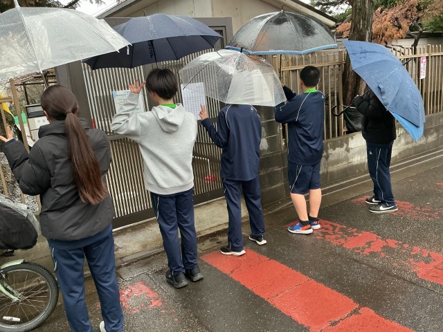 保育園の前で思い思いのポーズをとる5人の部員の後ろ姿