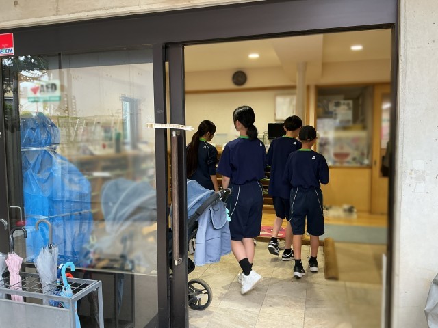 保育園を訪れる部員たちの背中
